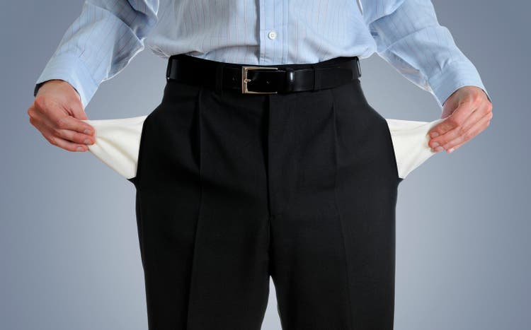 Man pulling out empty pockets against dark gray background