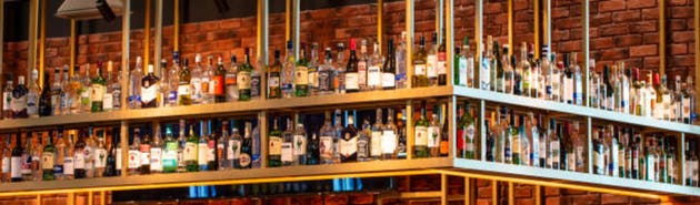 The Bottles Of Alcohol And Spirits On Backlight Shelves At A Pub Or Bar.