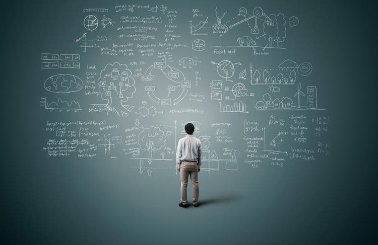 Man looking to formula and picture on blackboard