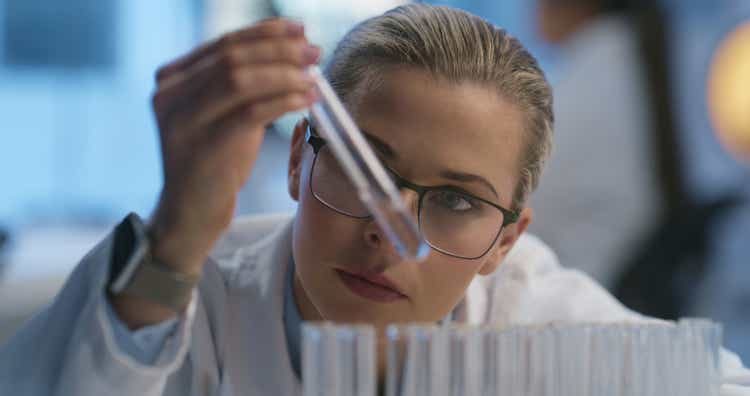 Science, test tube and face of woman check liquid solution, vaccine and study pharmaceutical product, biotech or assessment. Lab, pharma or chemist research clinic drugs, exam or chemical engineering