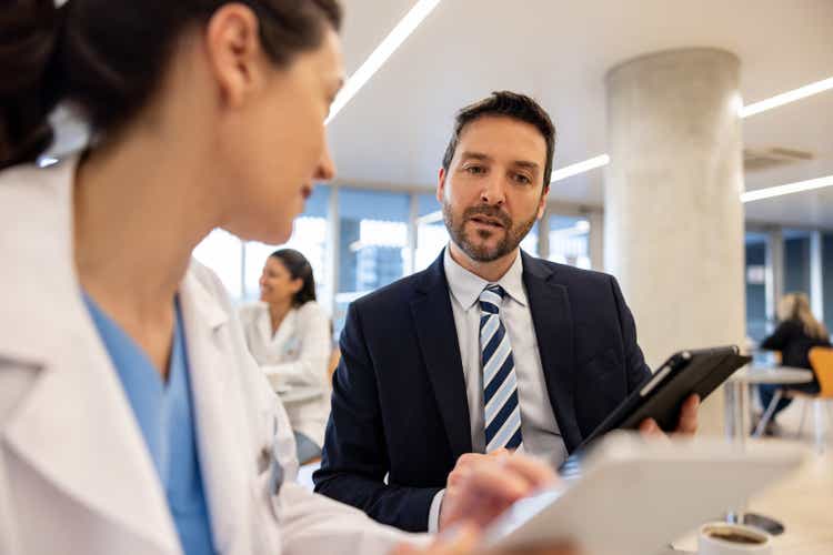 Hospital manager talking to a doctor and looking at a medical record