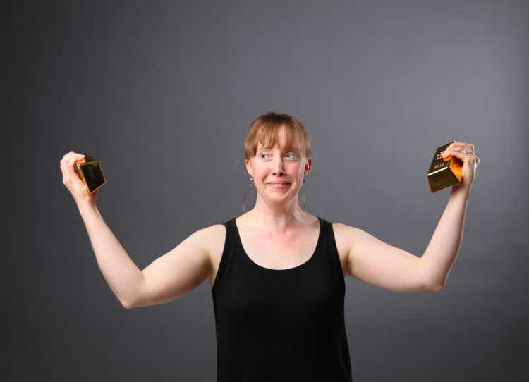 adult redhead caucasian female lifts gold bar like weights
