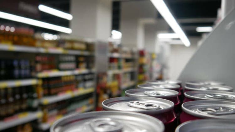 Close-up of many burgundy cans of alcohol or non-alcoholic drink in a supermarket