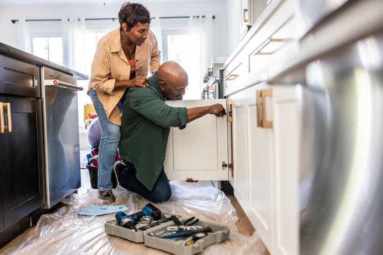 Senior couple repairing kitchen cabinet at home