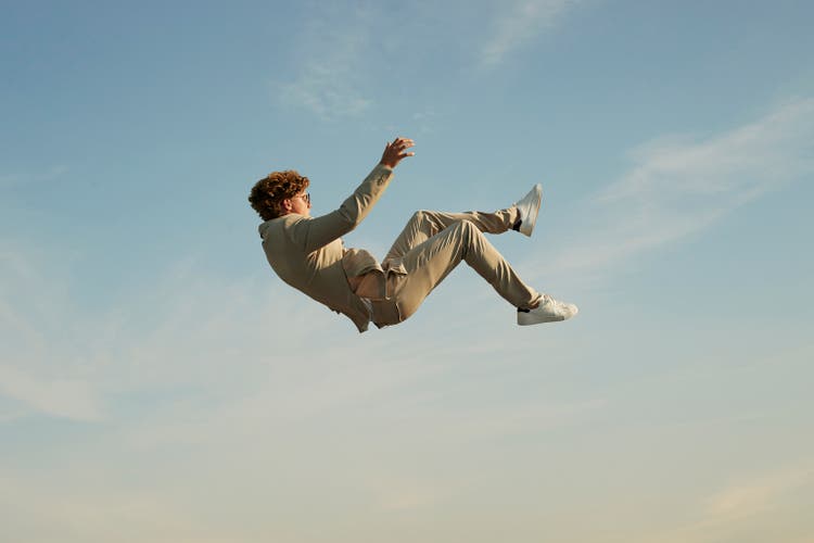 Young man falling against clear blue sky