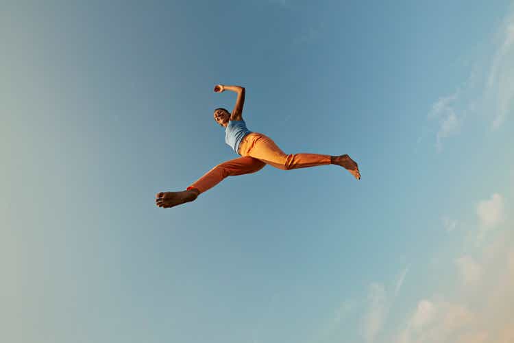 Smiling woman jumping with legs apart