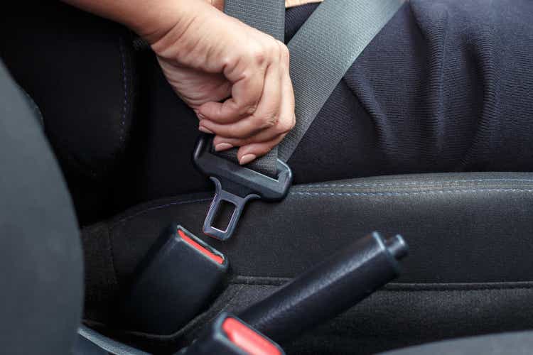 Close up of woman hand buckle the car safety belt.