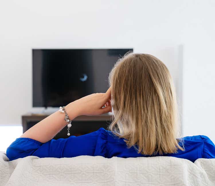 Woman is waiting for a movie to load on the TV. Slow Internet connection.