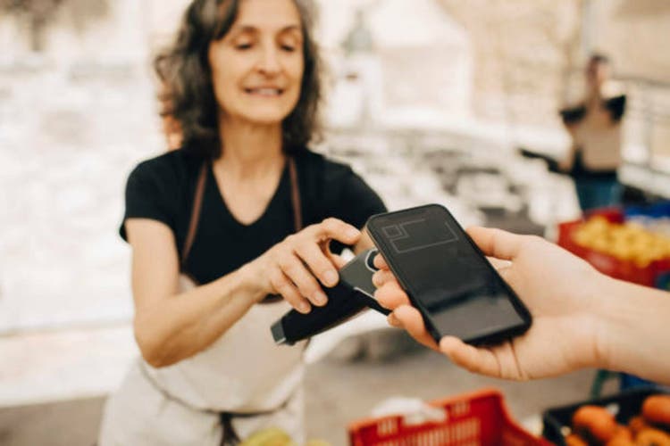 Cropped hand of woman paying through smart phone at market stall in city