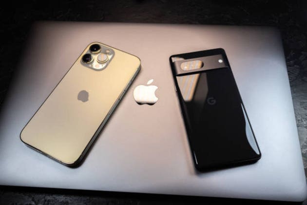 Kyiv, Ukraine - October 20, 2023 : Modern smartphone Apple iPhone 15 Pro and Apple Macbook Pro laptop near Google Pixel. Two biggest american company in modern technology.