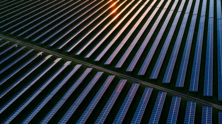 Drone view over a field of solar panels at sunset