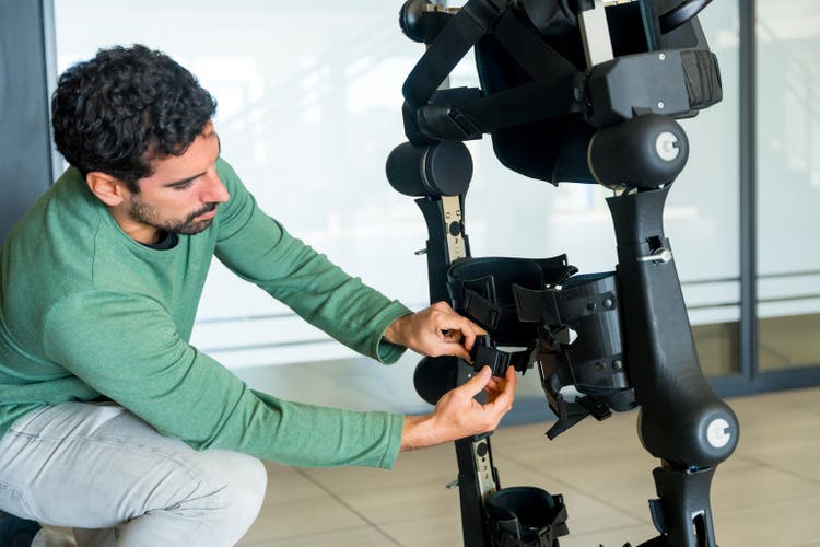 Mechanical exoskeleton engineer checking the mechanisms before the arrival of patients. Physiotherapy in a modern hospital