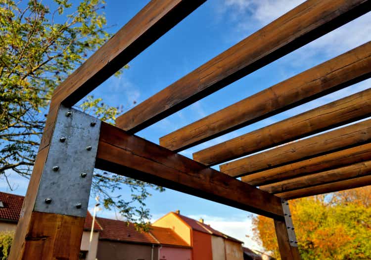 terrace with wooden pergola and plexiglass roof. vines are straining, crawling under the beams. garden or park. sitting with dry wall wine region. restaurant countryside france, truss