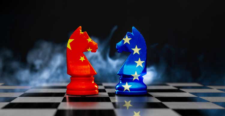 Two king chess pieces textured with European union and Chinese flags on black background with smoke