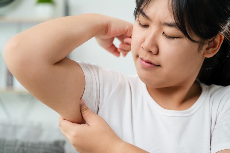 Close up of Chubby woman pinching upper arm fat. weight loss concept.