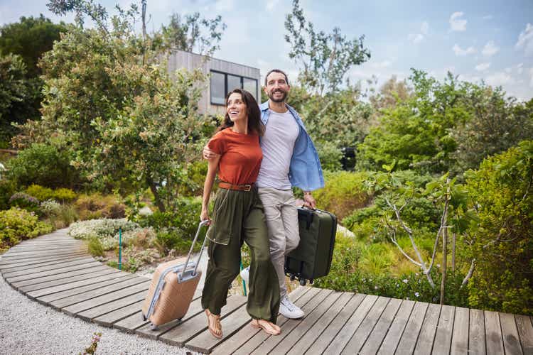 Smiling couple arriving with suitcases at their vacation accommodation