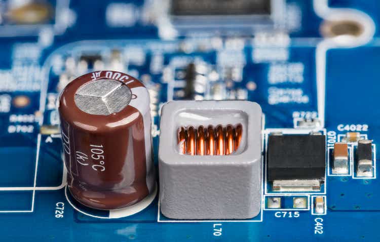 Closeup of inductor, electrolytic capacitor or transistor on blurry PCB background