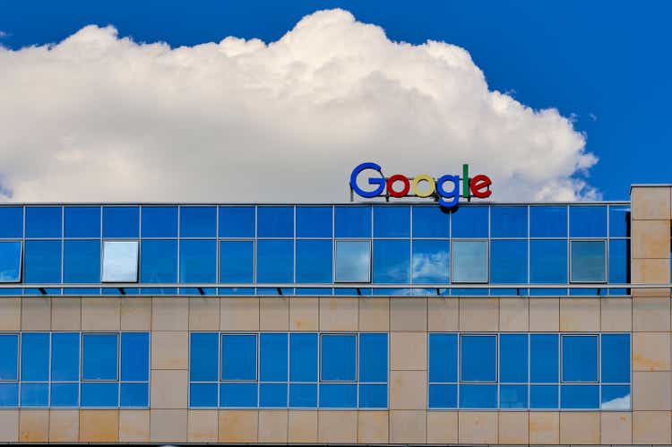 Google sign or logo on top of the office building. Blue sky, daytime, big white cloud.