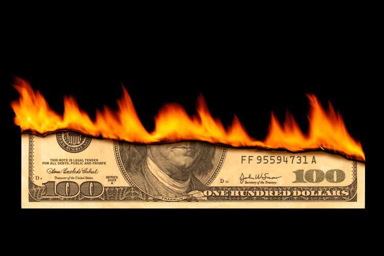 One hundred dollar bill on fire on black background