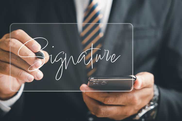 Businessman utilizes smartphone to sign electronic documents on virtual screen