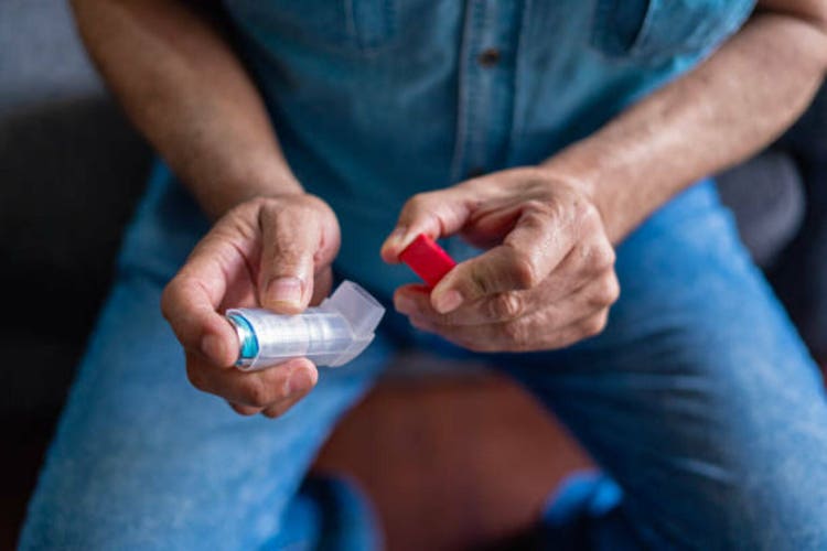 Close-up of an older man"s hands holding an asthma inhaler.
