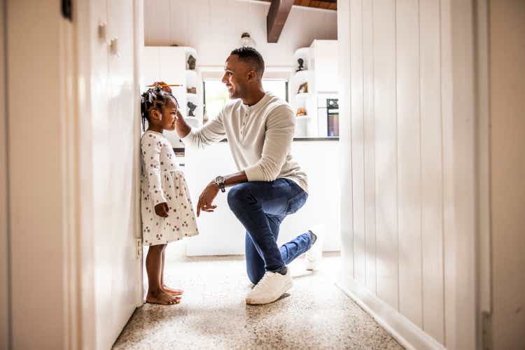 Father measuring daughter"s height on wall in kitchen