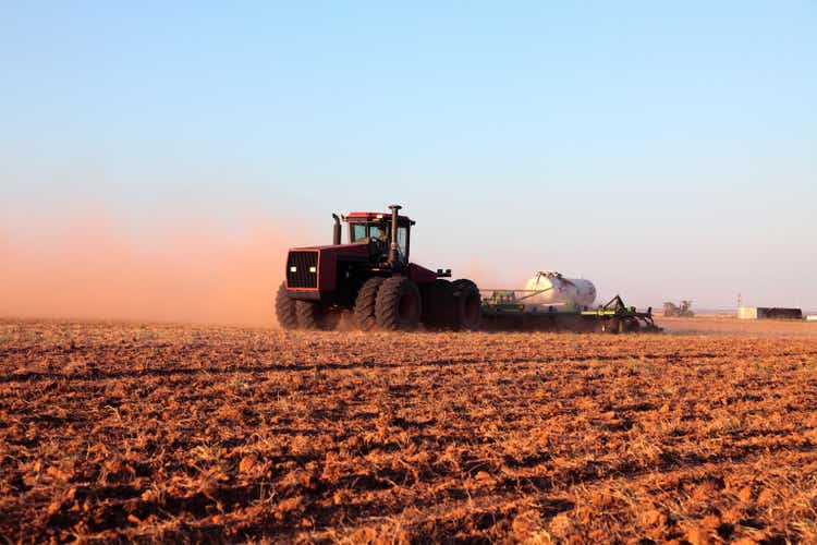 Agriculture: Farmer driving tractor with Fertilizer Tank in plowed field