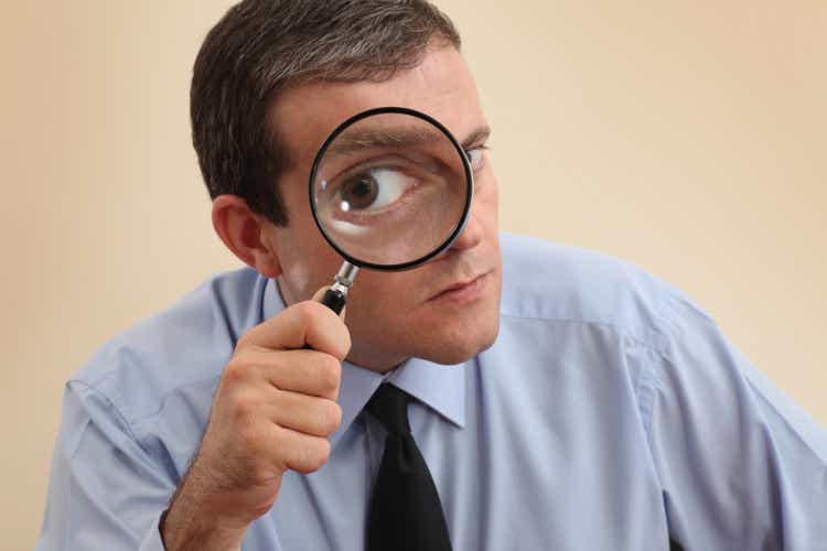 Businessman looking at camera through a magnifying glass