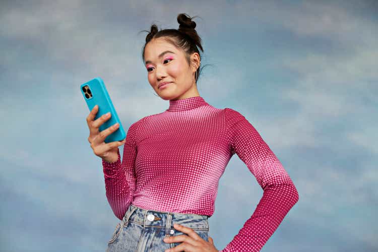 Teenage girl using mobile phone while standing on colorful background