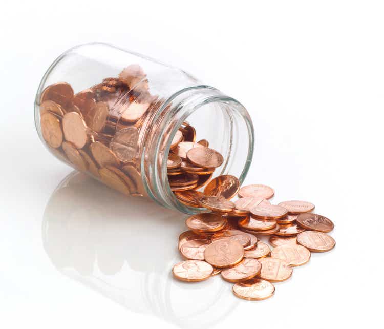 Jar of polished US pennies spilling out on white