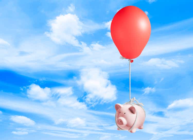 Piggy bank lifted up into sky by inflated balloon