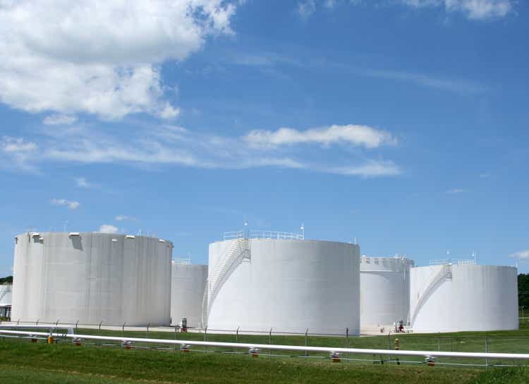 Several white storage tanks in a grassy field
