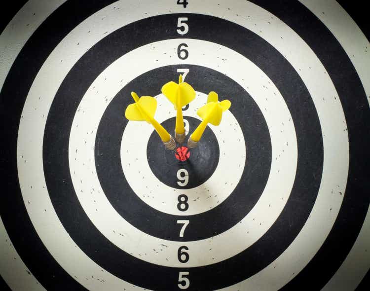Three yellow darts in the black and white dartboard bullseye