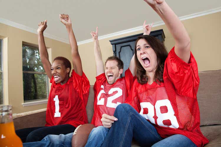 Excited sports fans cheering their football team on at home
