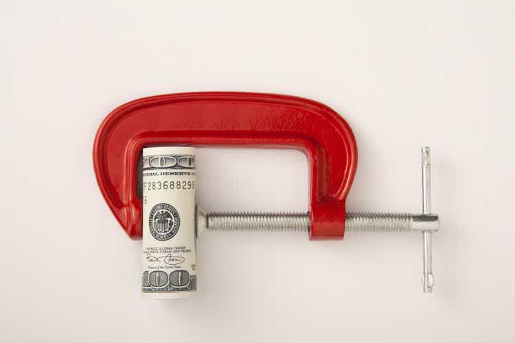 Money roll clamped in a red clamp on a white background