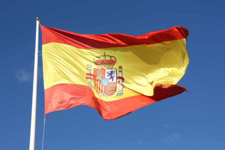 Flag of Spain waving in breeze with blue sky behind