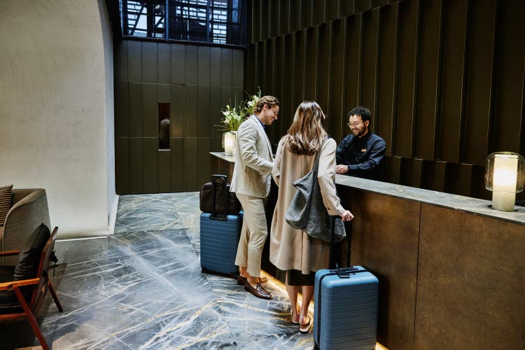 Wide shot couple being assisted with check in at hotel front desk
