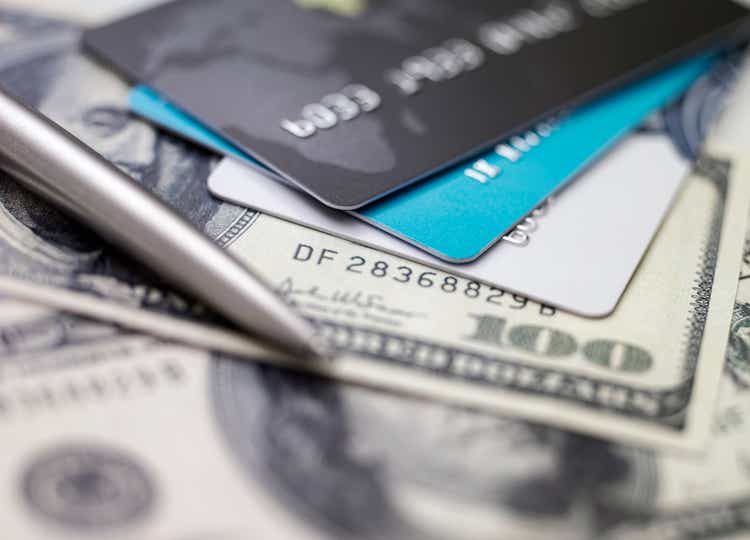 Three credit cards piled on top of dollar bills