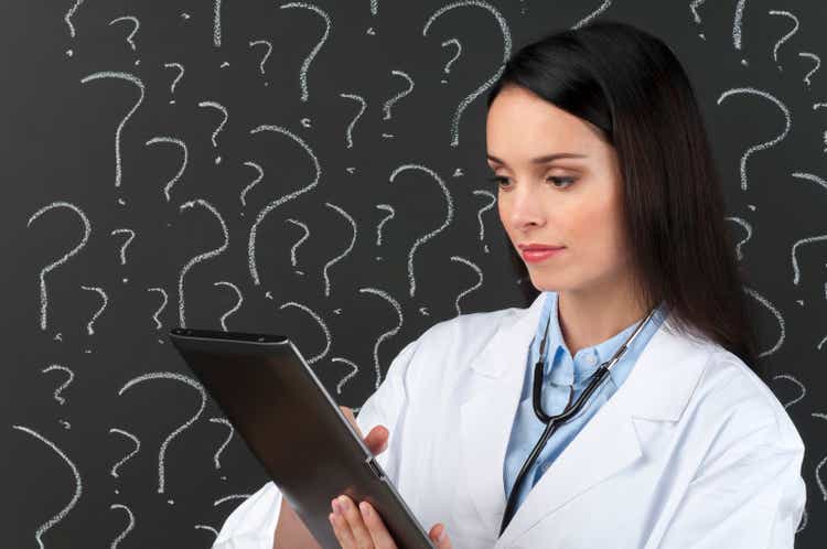 Female doctor with digital tablet in front of question marks