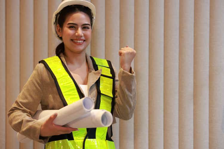 Businesswoman in green safety vest and white hat, engineering and business concept