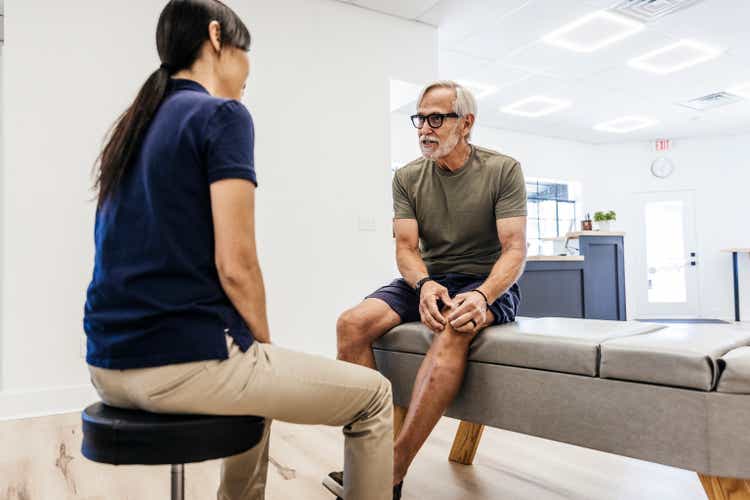 Senior man discussing with chiropractor at clinic