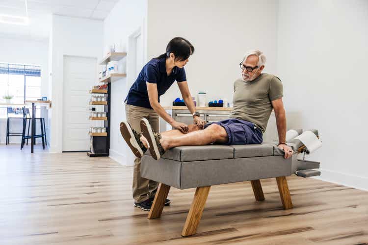 Female osteopath examining an elderly man