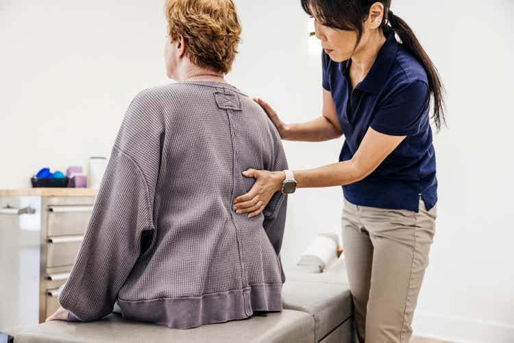 Female osteopath examining senior woman