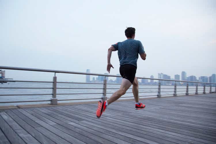 Man running on pier in front of city skyline