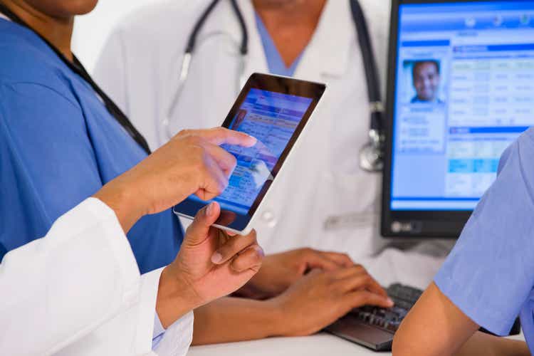 Doctors using digital tablet together in hospital