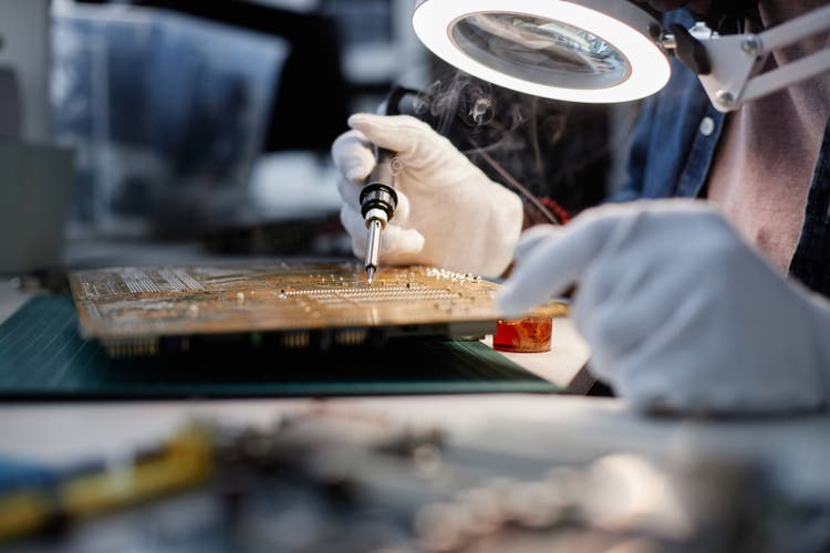 Unrecognizable Technician Fixing Circuit Board in Tech Shop
