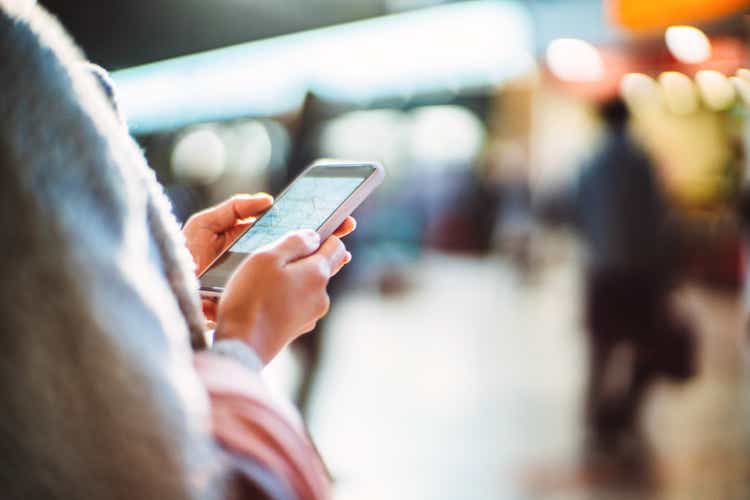 Cropped shot of a female traveller looking at rail map on smart phone while planning her journey at train station