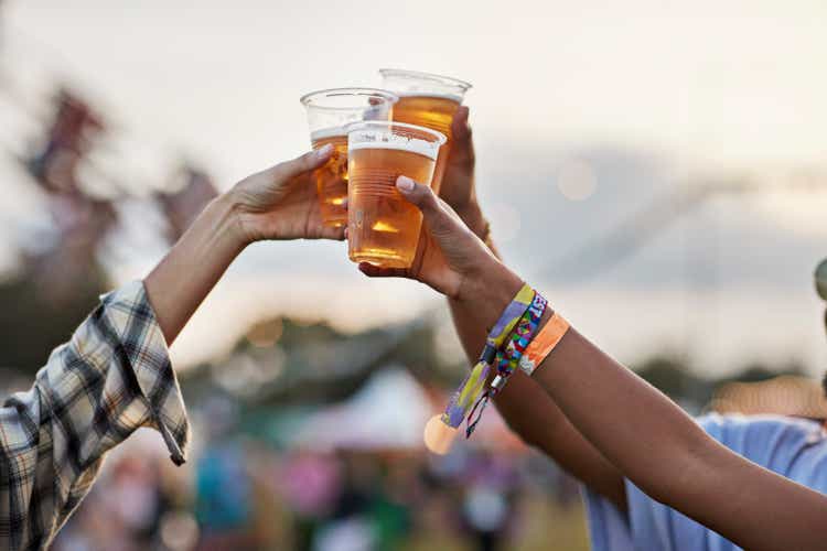 Hands of men and women toasting beer at music festival