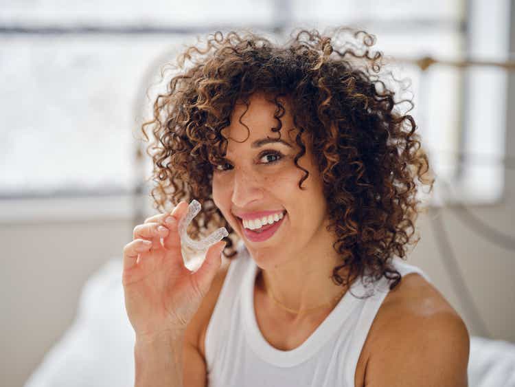 Woman in Bed in the Morning Using Clear Teeth Aligners