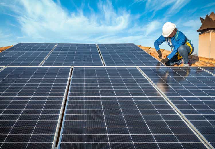 Professional female worker installing solar panels on the roof of a house